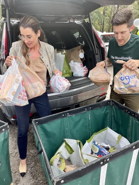 Michelle Little, VP Community Affairs and Community Giving representing Waste Connections donates food collected from their headquarters to Interfaith volunteer, Ian Ramirez, Interfaith Development Committee.